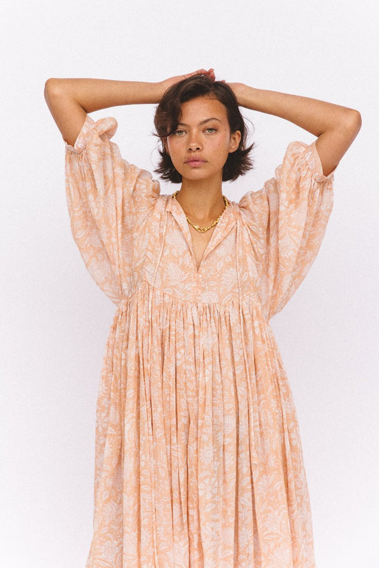 Daughters of India Kyra Midi Dress in Apricot Blush — studio arms raised, V-neckline and billowed sleeves, floral print
