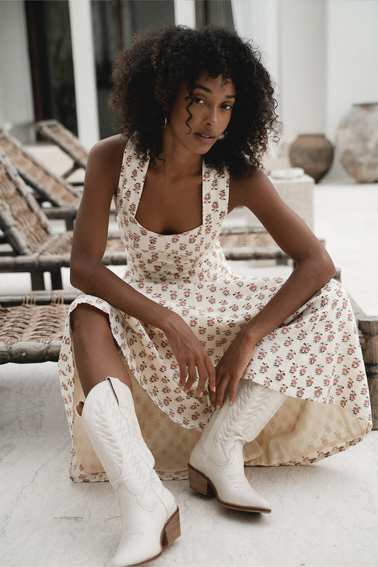 Lalika Dress Peony — side view walking by villa pool, peony hand block print cotton wrap dress with flowing A-line midi skirt, cream with pink floral motifs, tropical pool setting | Daughters of India